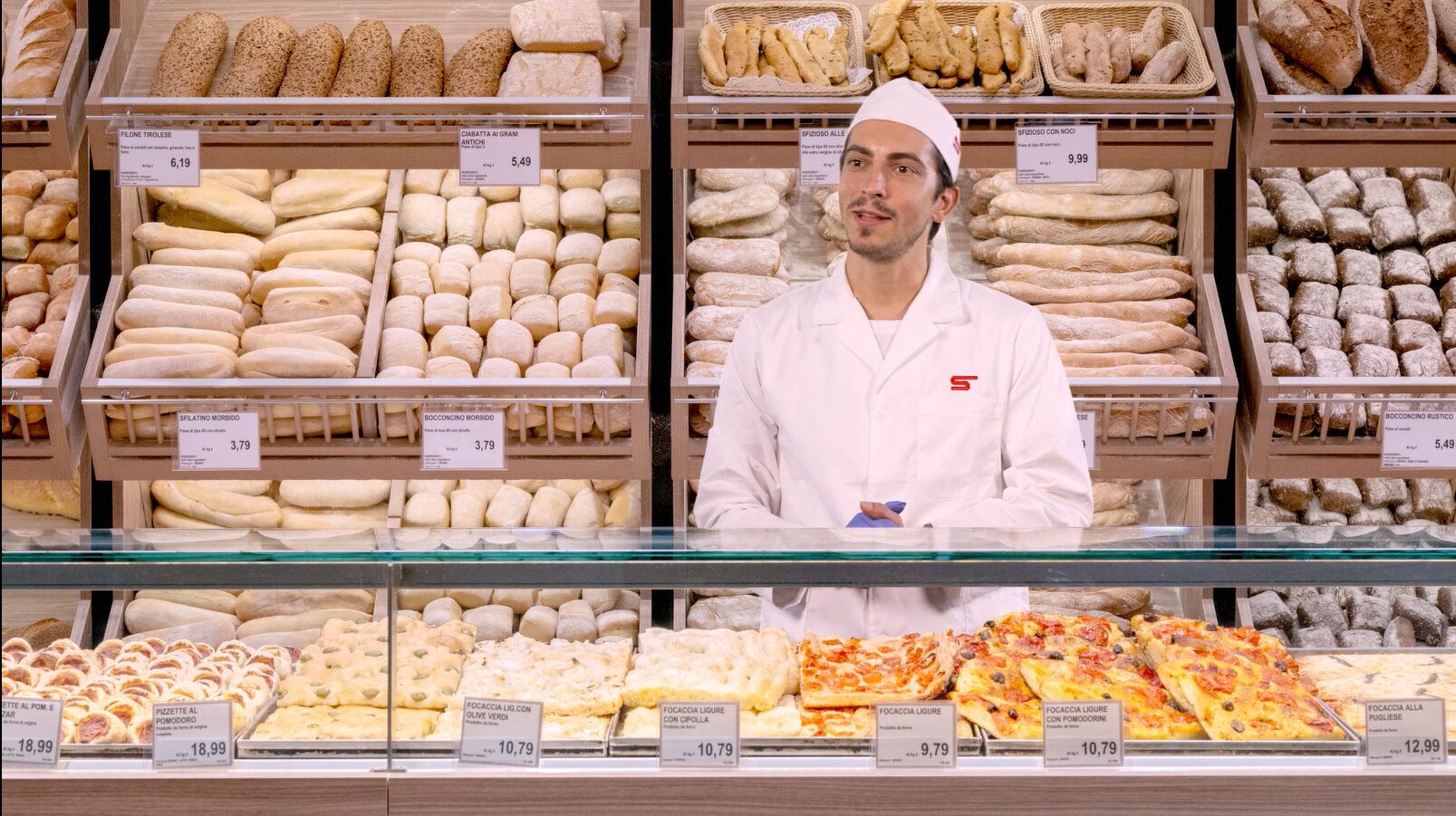 Operatore in divisa inserito digitalmente nel reparto panetteria di un supermercato, immagine finale ottenuta con post produzione e compositing video per un progetto di digital learning di Siquis.
