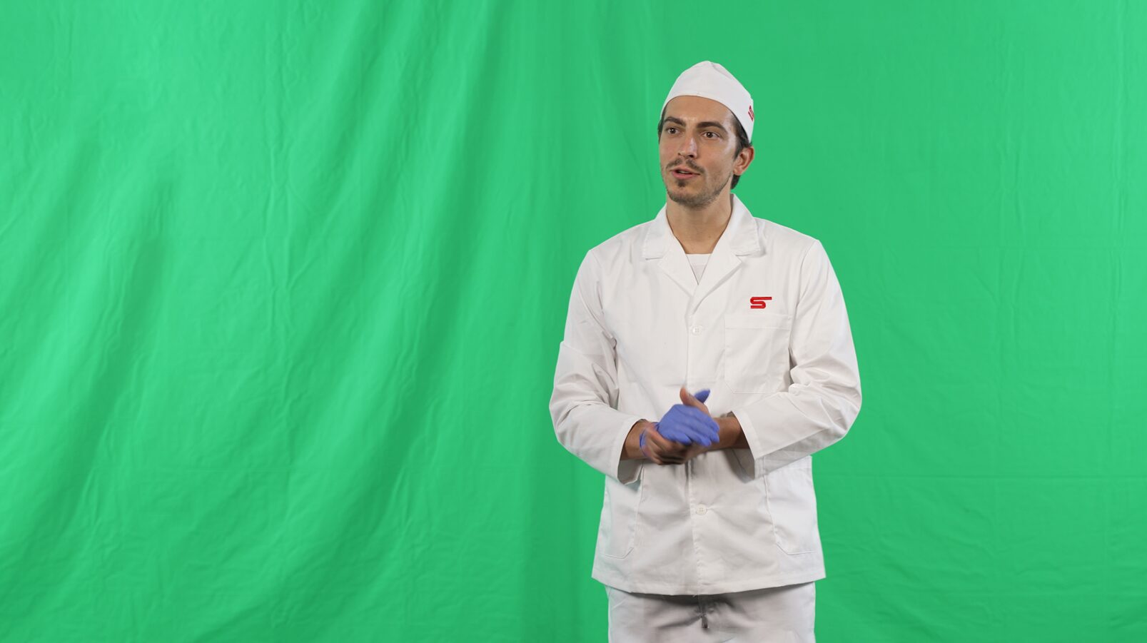 Operatore in divisa da supermercato ripreso davanti a green screen durante la registrazione di un contenuto video, immagine che rappresenta la fase originale di produzione per progetti di digital learning di Siquis.